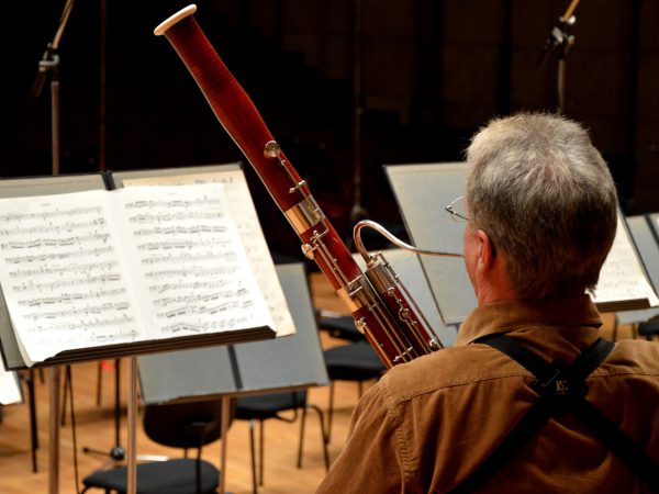 Bassoonist in an orchestra reading sheet music and playing the bassoon.