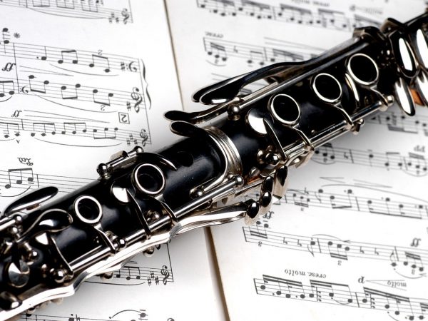 A black and chrome accented clarinet laying on top of sheet music.