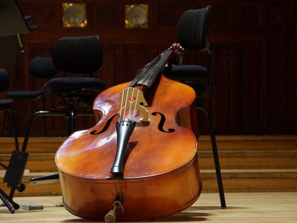 A double upright bass leaning against a chair in a local rehearsal hall.