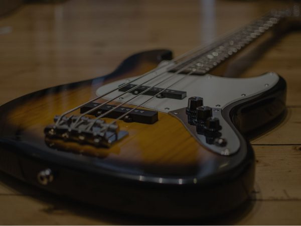 A brown/white electric bass laying on the floor.