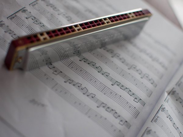 A chrome harmonica standing on a page of sheet music.
