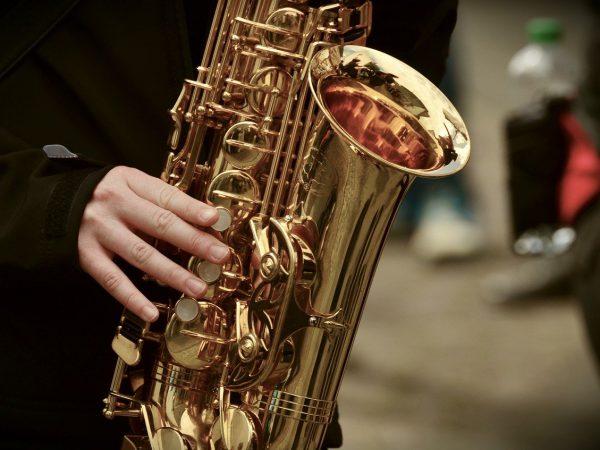 A musician holding the saxophone upright while playing it.